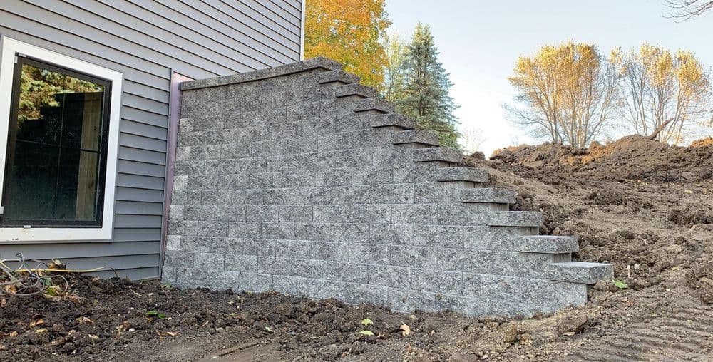 Gray stone steps leading from a house to a landscaped yard with trees in the background.