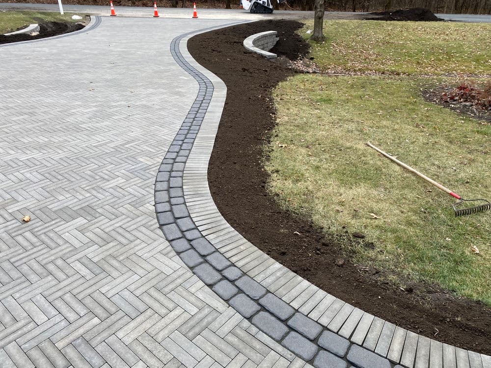 Curved stone pathway with freshly laid tiles and prepared garden bed for planting.