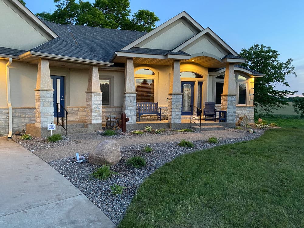 Charming residential home entrance with landscaped yard and evening lighting.