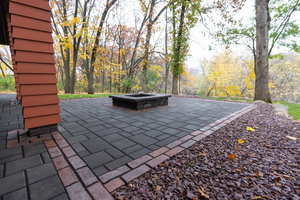 Paved patio with a fire pit surrounded by autumn trees and colorful foliage.