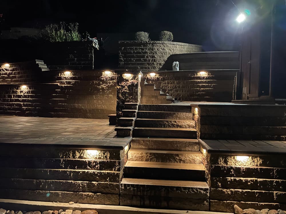Illuminated outdoor stairs and patio at night with decorative lighting.