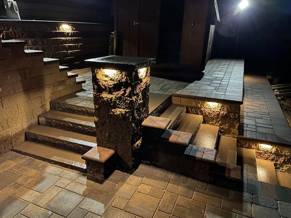 Illuminated outdoor stone steps and pathway at night with decorative lighting features.