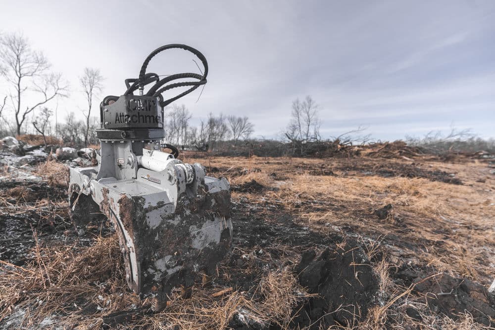 Close-up of a heavy-duty land clearing attachment in a burned landscape.