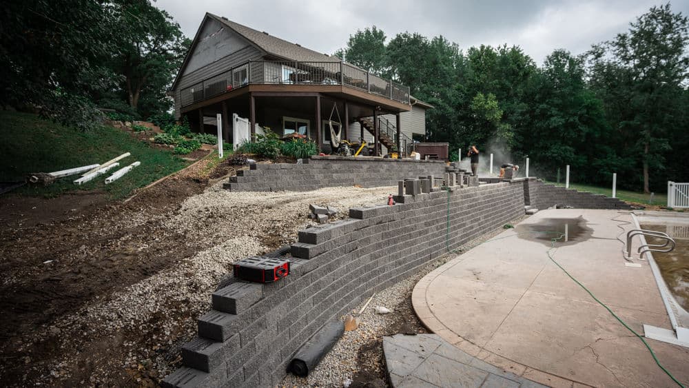 Landscape construction with retaining wall and multi-level yard behind a house.