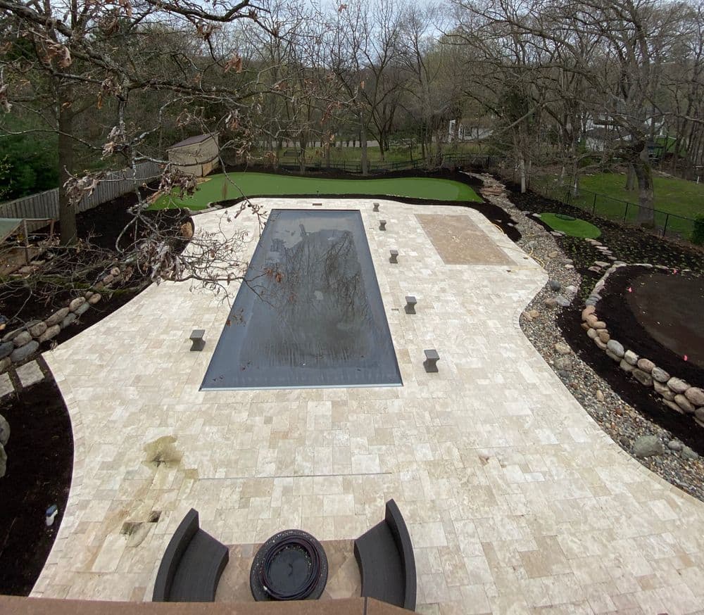 Aerial view of a modern swimming pool surrounded by natural landscaping and patio area.