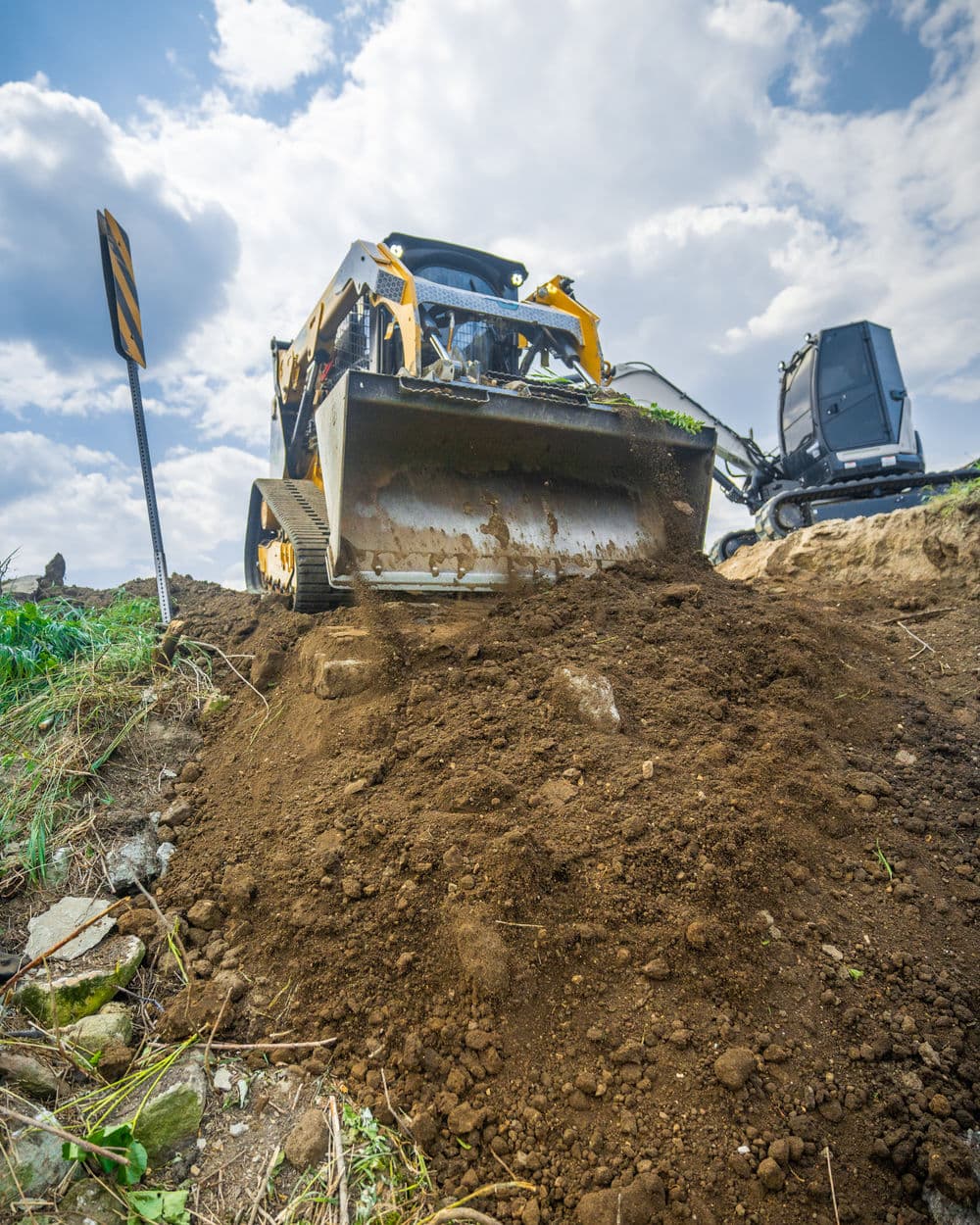 Bulldozer moving dirt on a construction site under a cloudy sky.
